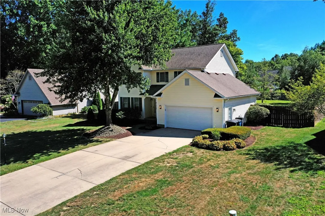 Traditional-style home with a garage, driveway, and roof with shingles
