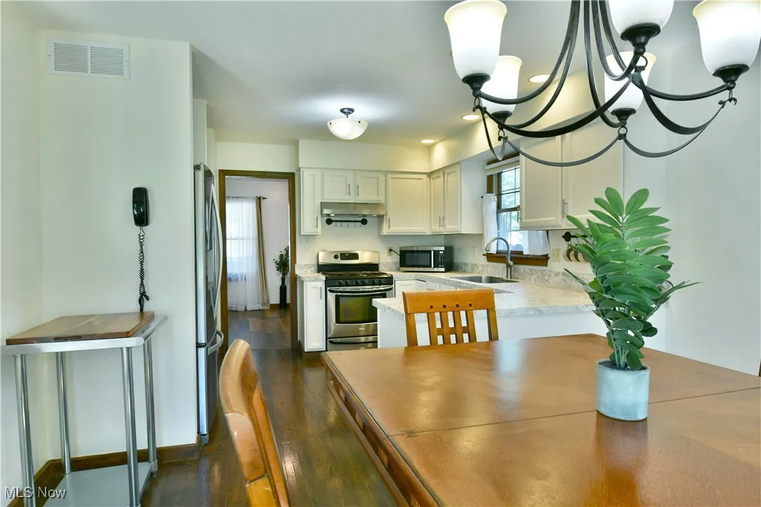 Kitchen featuring a chandelier, stainless steel appliances, dark wood-type flooring, white cabinets, and recessed lighting