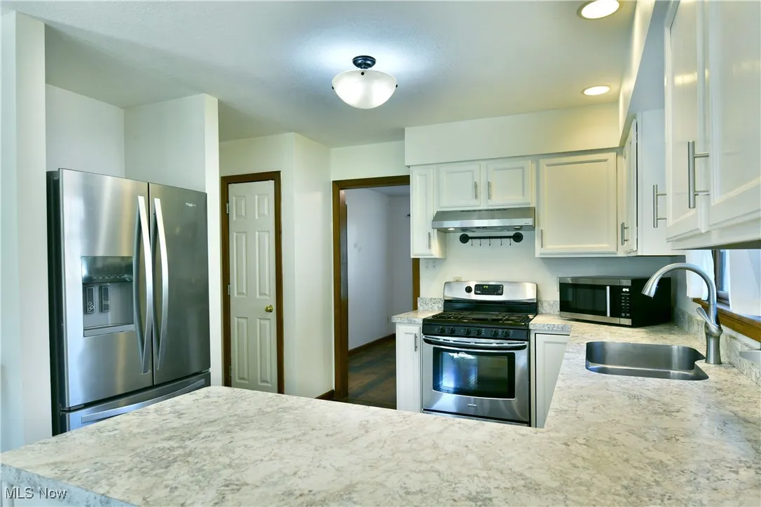 Kitchen with stainless steel appliances, light countertops, white cabinetry, a peninsula, and recessed lighting