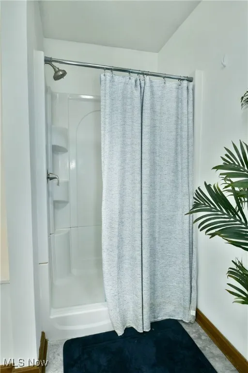 Bathroom featuring a stall shower and baseboards
