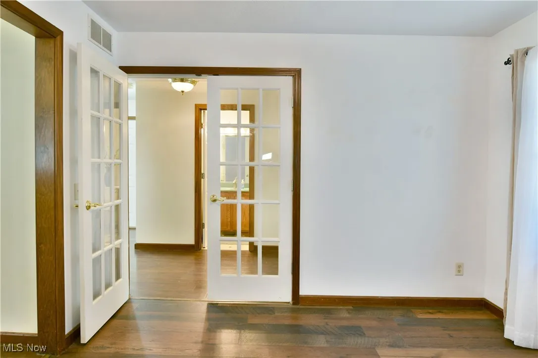 Empty room with dark wood-style flooring and french doors