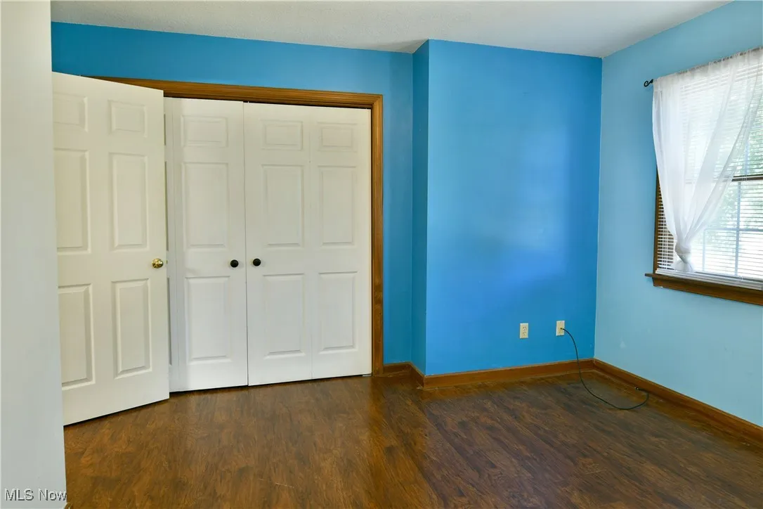 Unfurnished bedroom with dark wood finished floors and a closet