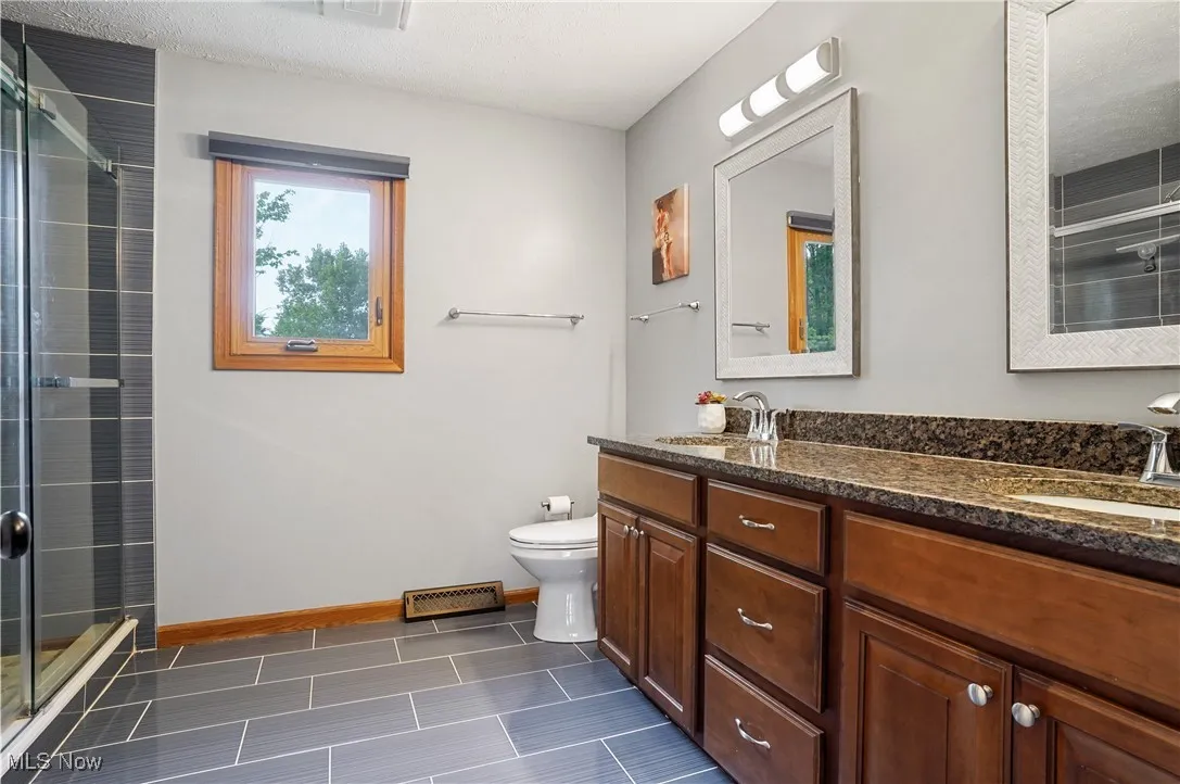 Completely updated primary bathroom with double vanity and walk in tiled shower
