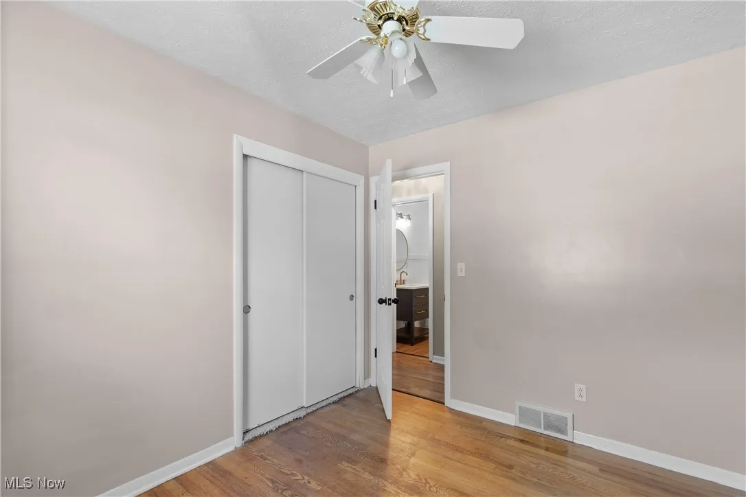Unfurnished bedroom with wood finished floors, a closet, a textured ceiling, and a ceiling fan