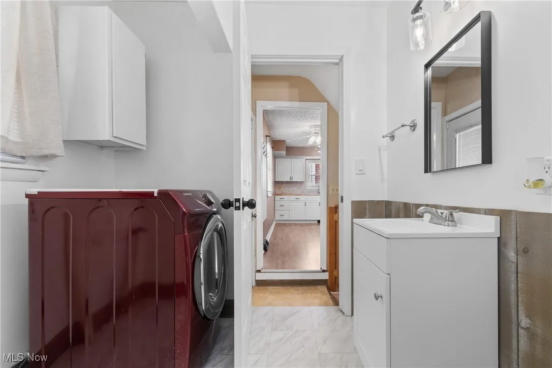 Bathroom featuring washer / clothes dryer, vanity, light marble finish flooring, and wainscoting