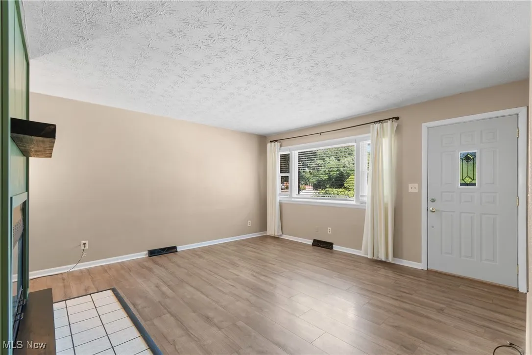 Unfurnished living room with light wood-style floors and a textured ceiling