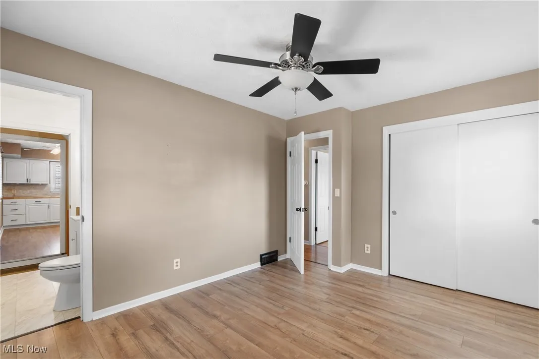 Unfurnished bedroom featuring light wood-style floors, ceiling fan, a closet, and connected bathroom