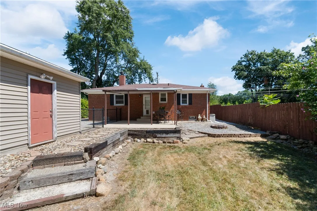 Back of property featuring an outdoor fire pit, a patio, brick siding, a chimney, and a fenced backyard