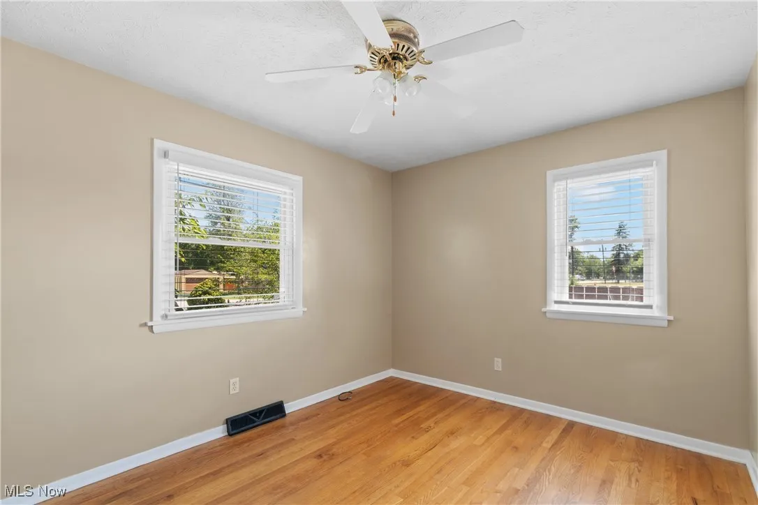 Empty room with light wood-type flooring, plenty of natural light, a ceiling fan, and a textured ceiling