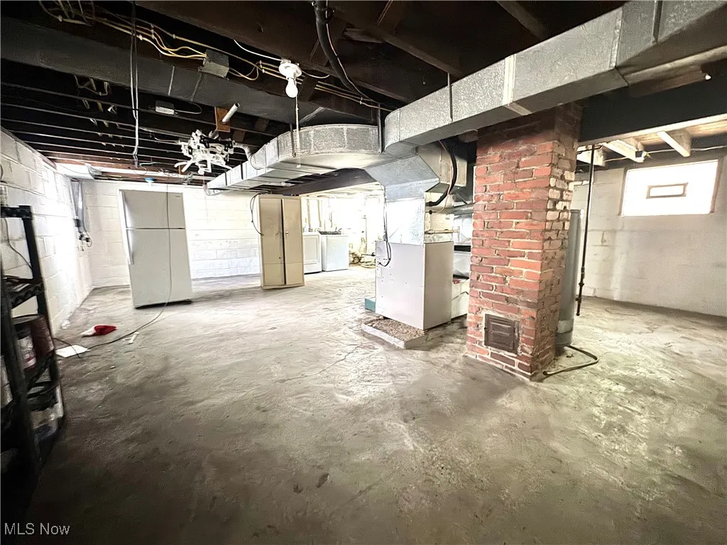 Below grade area with heating unit, freestanding refrigerator, washer / dryer, and water heater