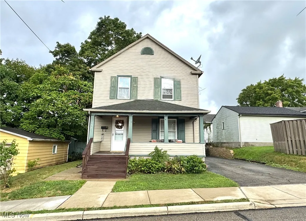 Traditional style home with covered porch and a front yard