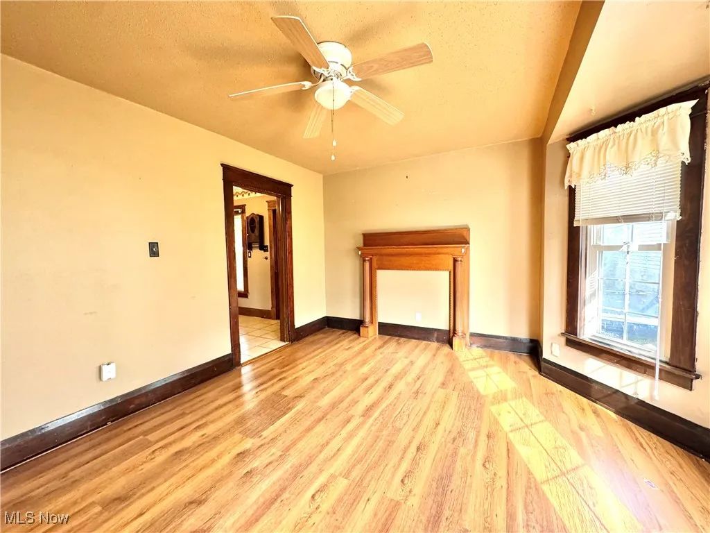 Unfurnished living room featuring light wood finished floors, ceiling fan, and a textured ceiling