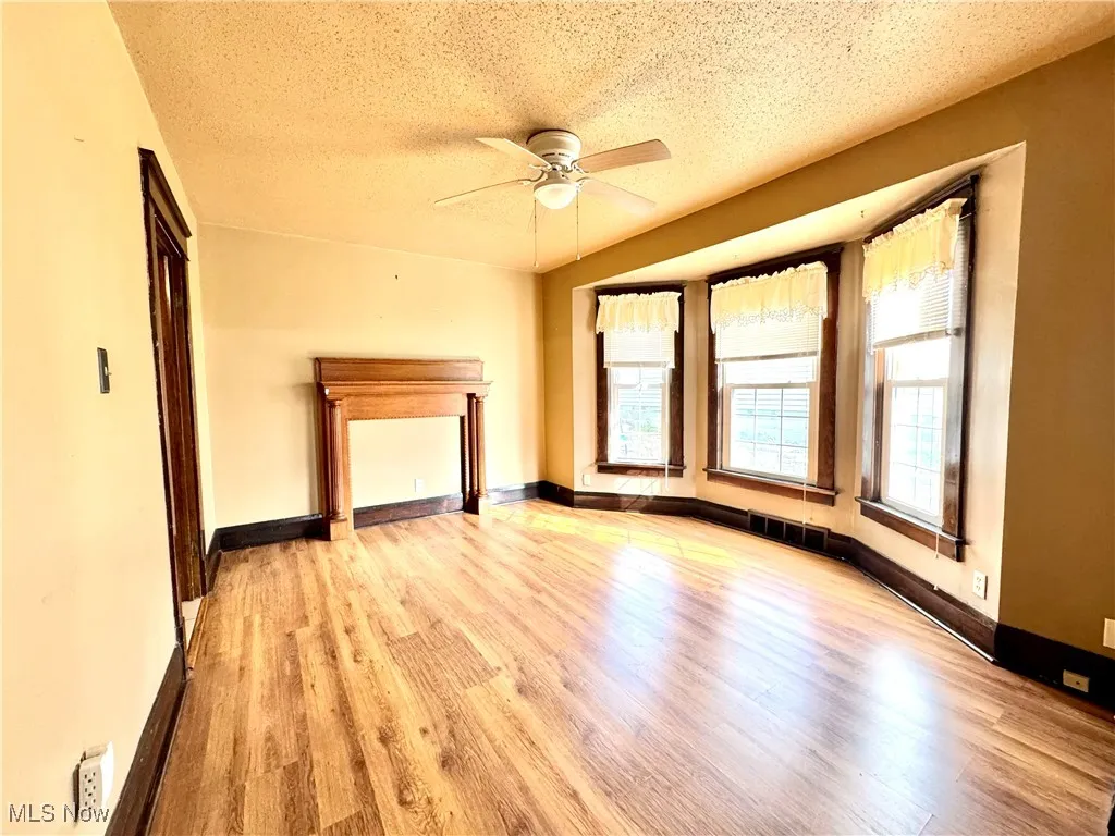 Unfurnished living room featuring a textured ceiling, light wood-style floors, and ceiling fan