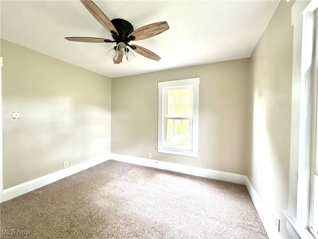 Carpeted spare room with baseboards and ceiling fan