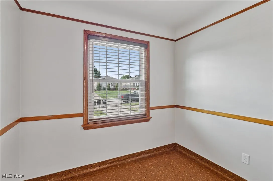 Unfurnished room featuring baseboards and speckled floor