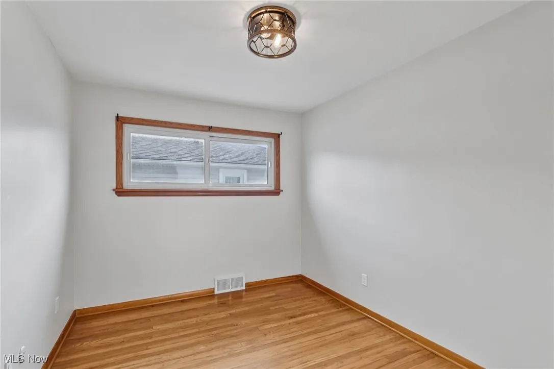 Spare room featuring light wood-style flooring and baseboards