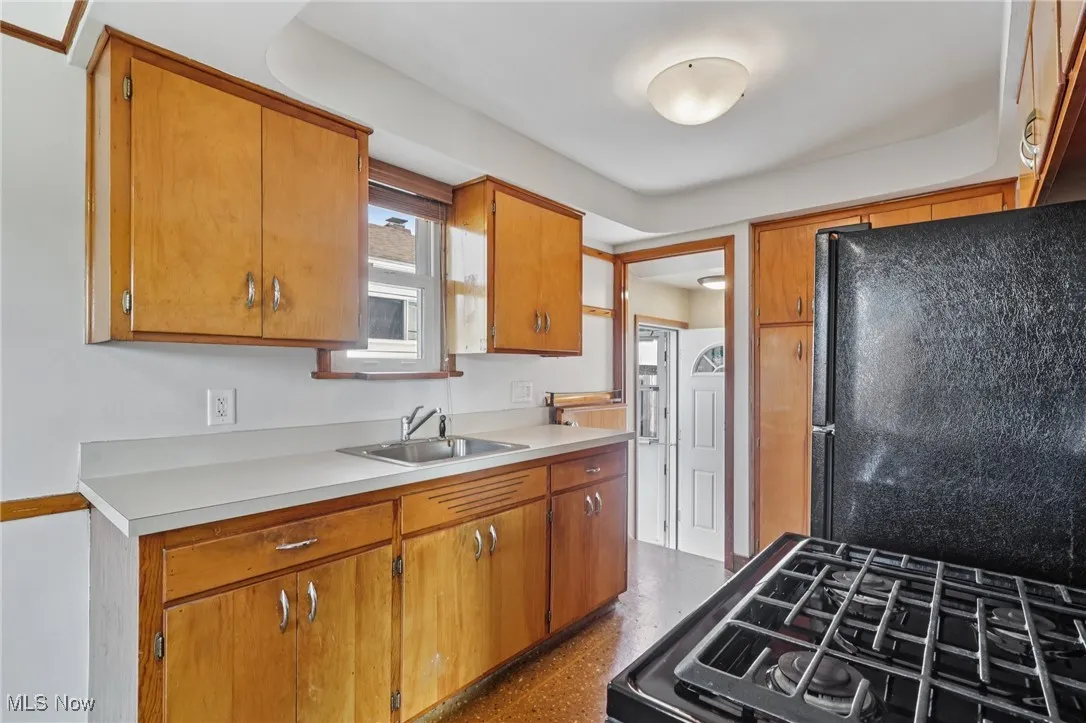 Kitchen featuring black appliances, brown cabinetry, and light countertops