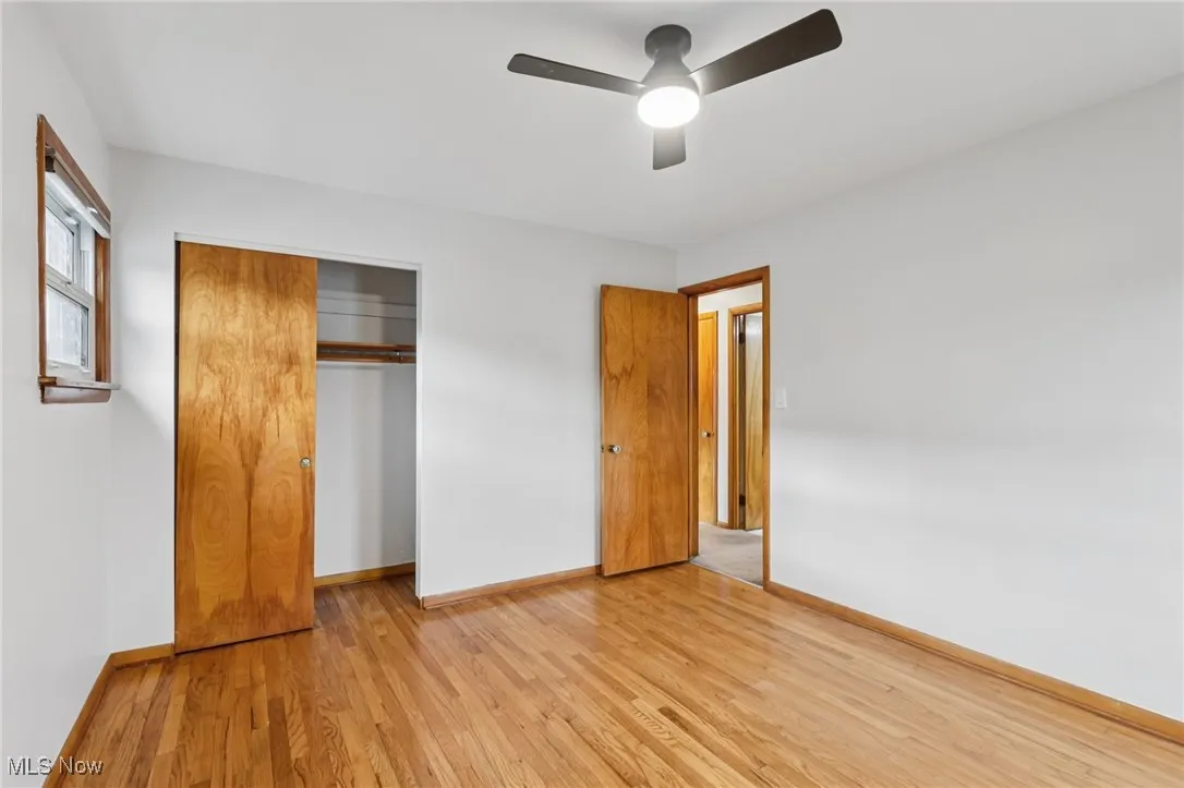 Unfurnished bedroom with light wood-style flooring, a closet, and a ceiling fan