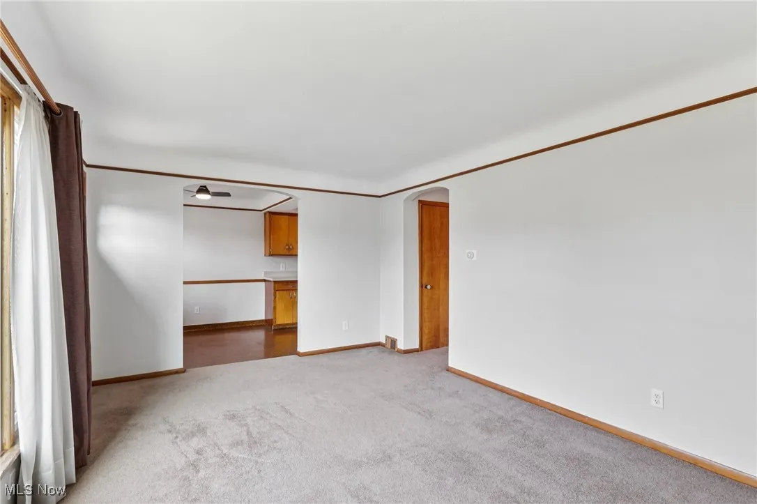 Spare room with arched walkways, light carpet, and ornamental molding