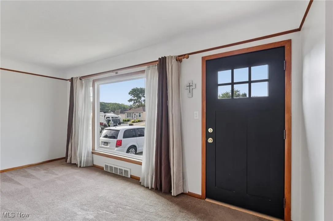 Foyer entrance with light colored carpet and baseboards