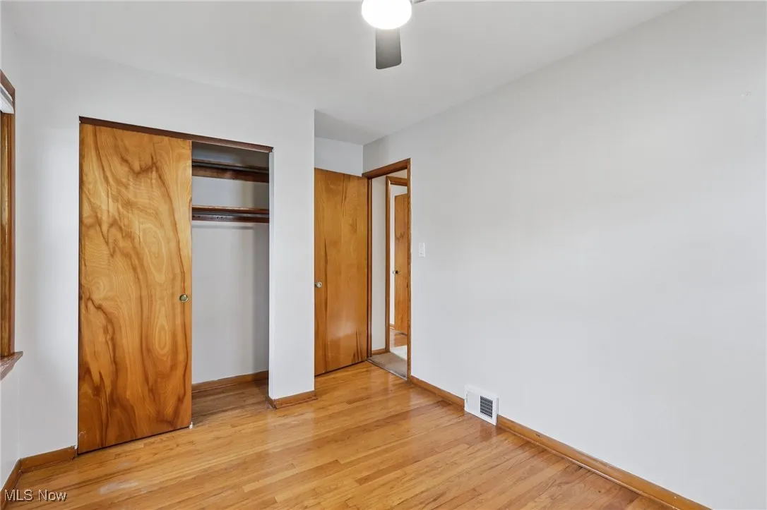 Unfurnished bedroom featuring light wood finished floors, a closet, and a ceiling fan
