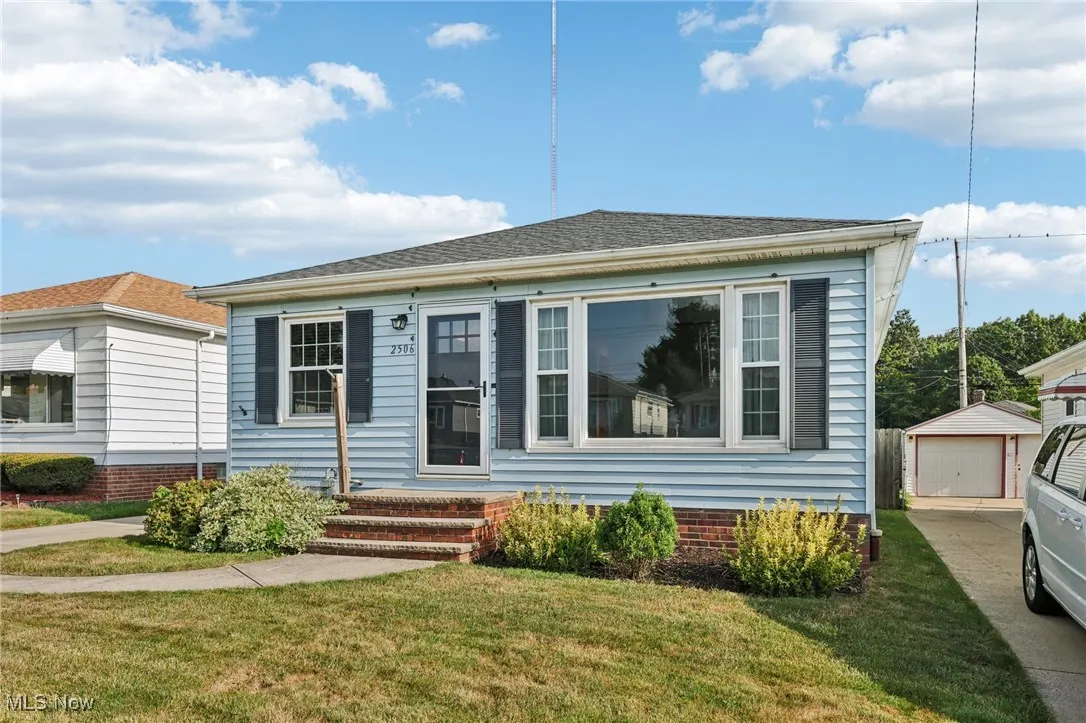 Bungalow-style house with an outbuilding, a front lawn, and a detached garage