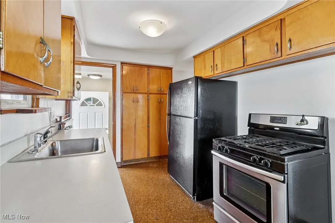 Kitchen with stainless steel range with gas stovetop, brown cabinets, and light countertops
