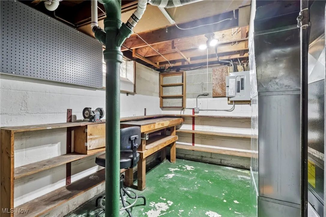 Unfinished below grade area featuring heating unit, a workshop area, and electric panel