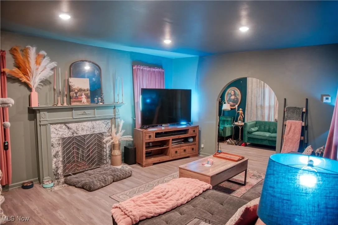 Living room featuring arched walkways, LVT floors, recessed lighting, and a high end fireplace