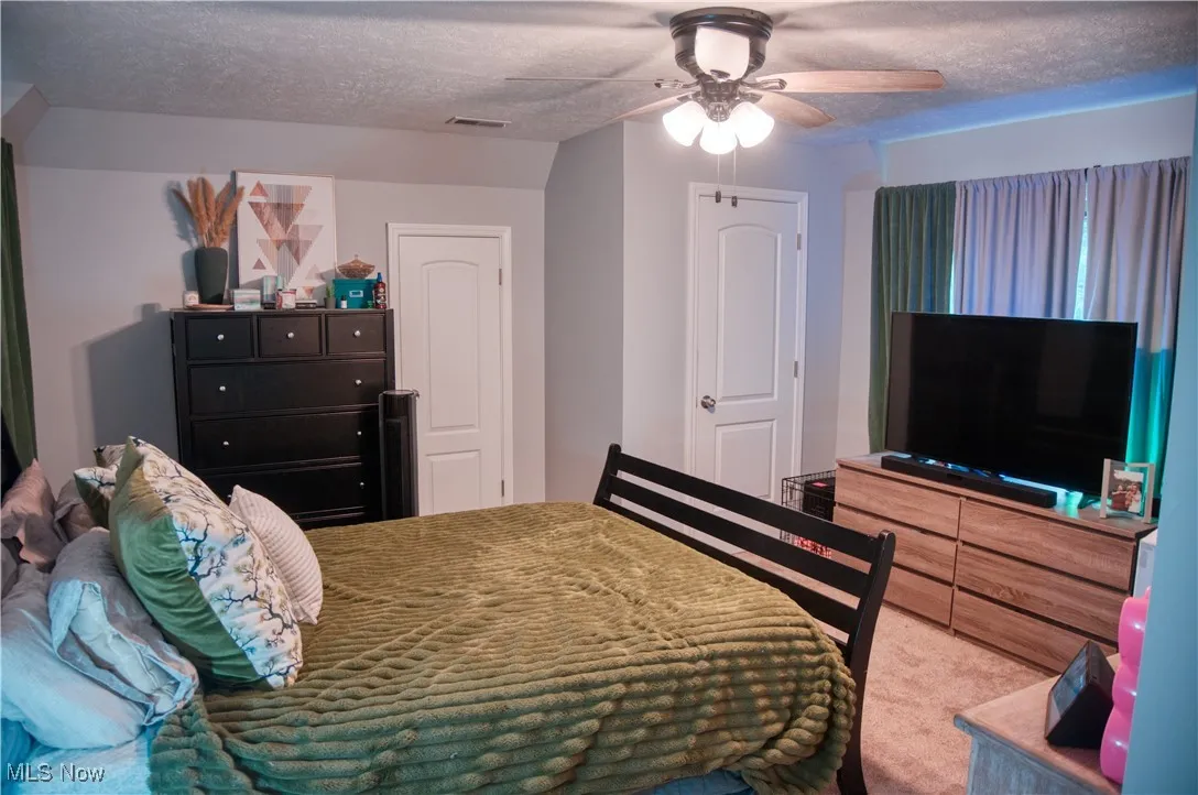 Master bedroom featuring light carpet and a textured ceiling