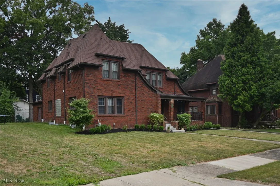 View of front of house featuring a front lawn, covered porch, brick siding, and chimney