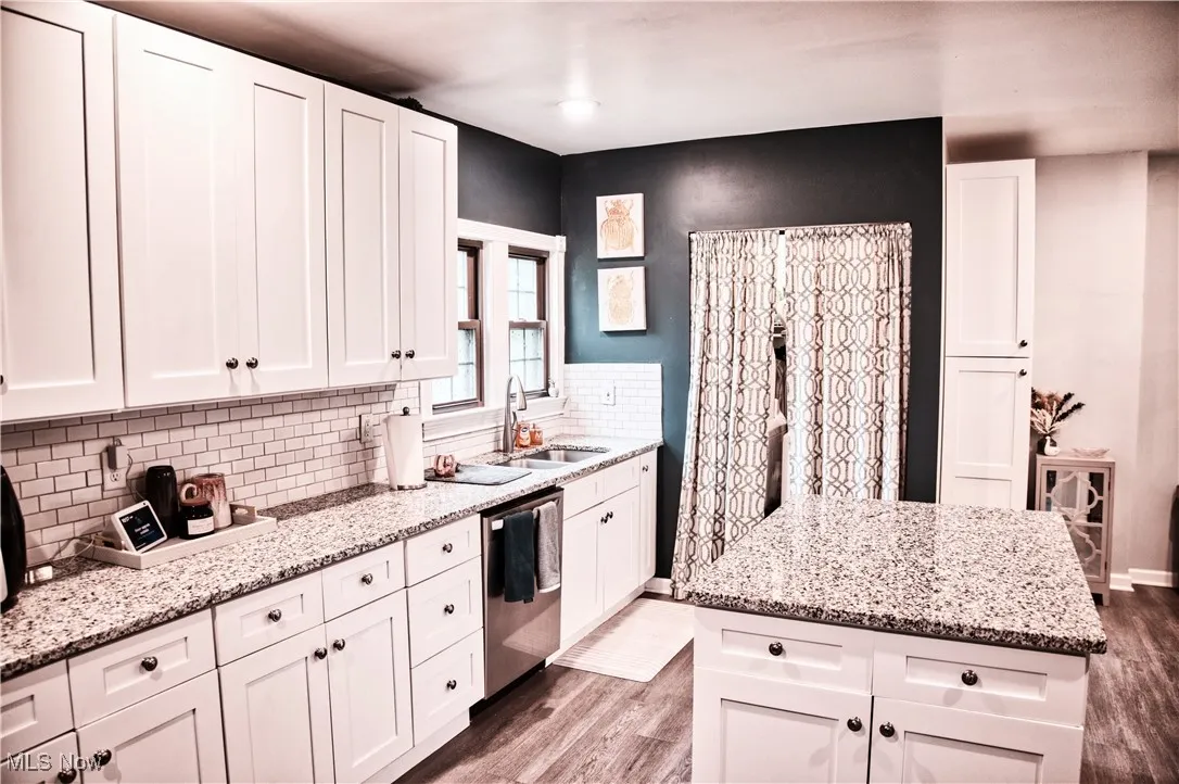 Kitchen featuring light LVT floors, white cabinetry, light stone counters, and a kitchen island