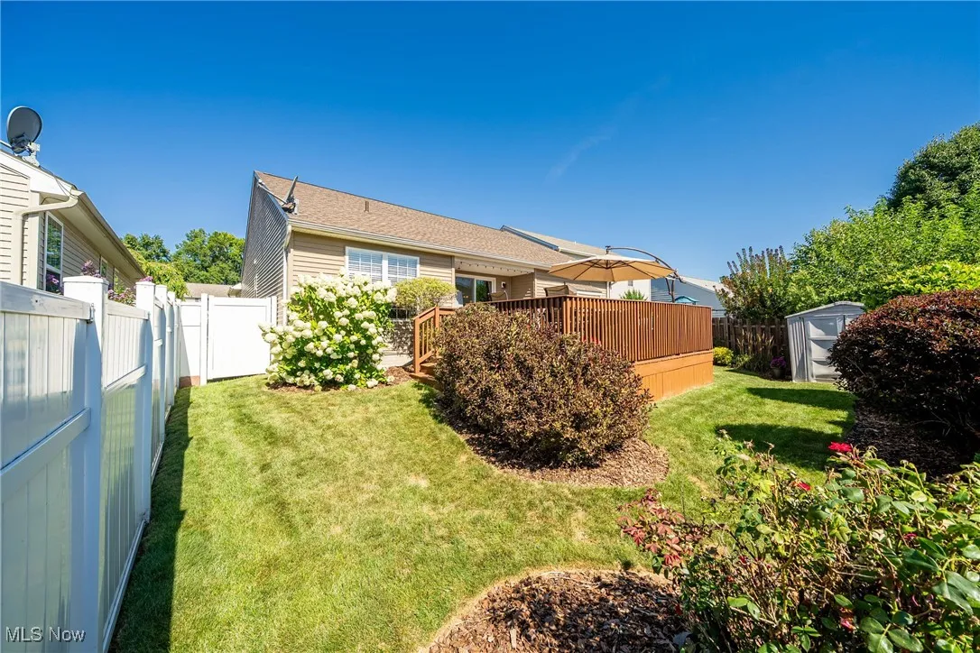 Back of house featuring a storage unit, a fenced backyard, and a deck