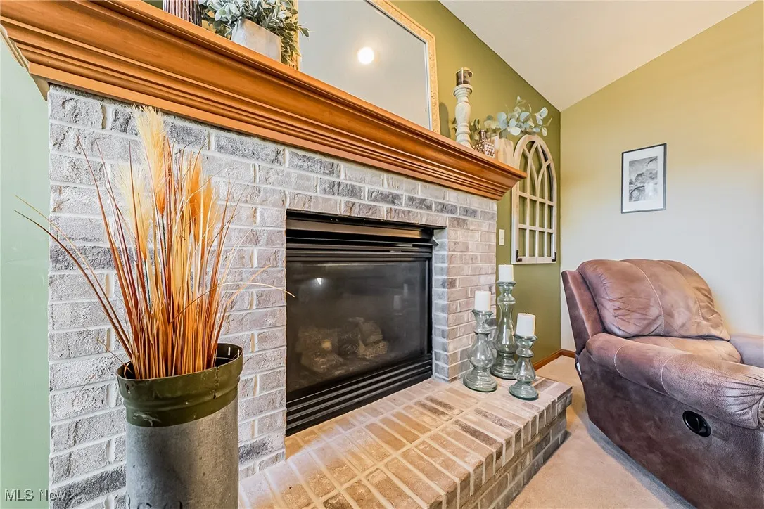 Living area with vaulted ceiling, a fireplace, and carpet