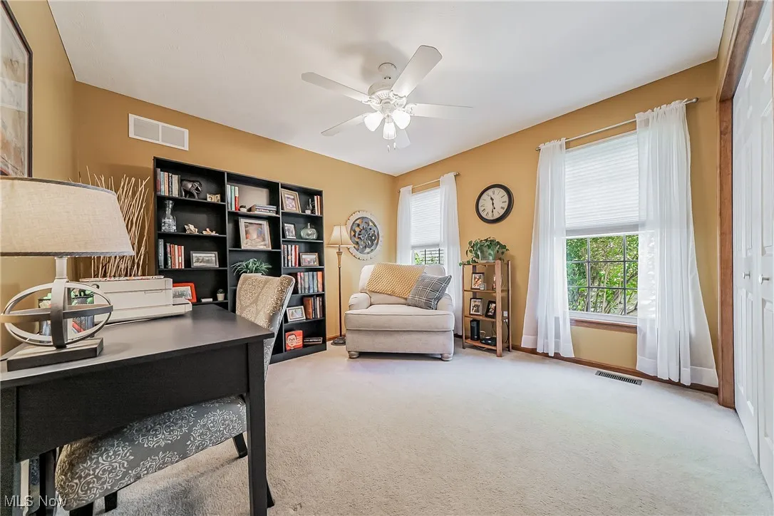 Office with light carpet and a ceiling fan