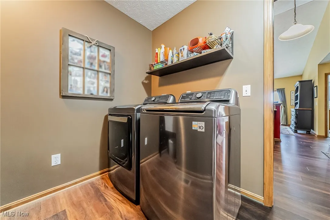 Washroom with dark wood finished floors, independent washer and dryer, and a textured ceiling