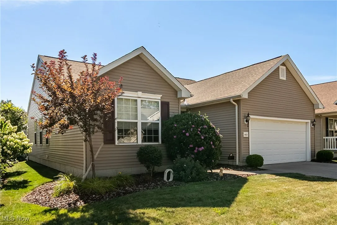 View of front of home featuring a garage, a front yard, concrete driveway, and roof with shingles