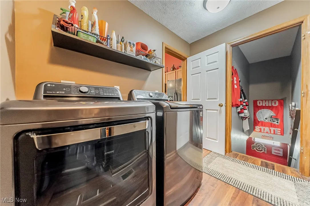 Laundry area with wood finished floors, a textured ceiling, and independent washer and dryer