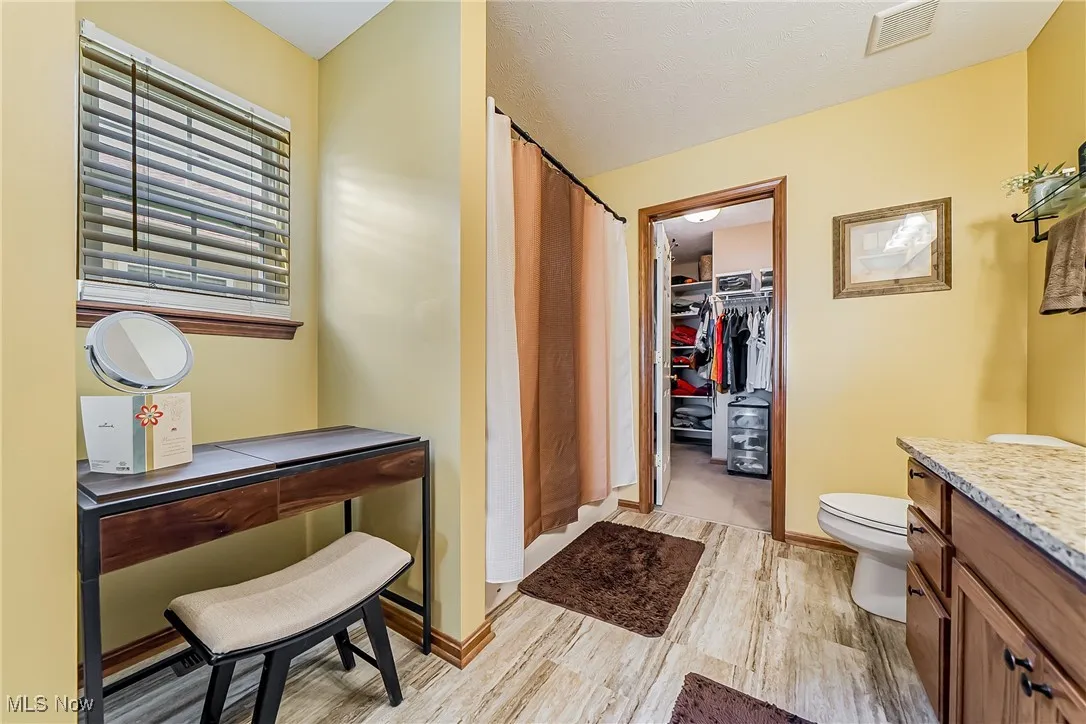 Bathroom featuring vanity, light wood-type flooring, a shower with shower curtain, and a walk in closet