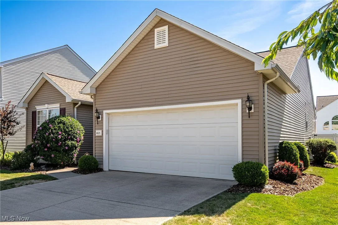 View of front of house with an attached garage, concrete driveway, and a shingled roof