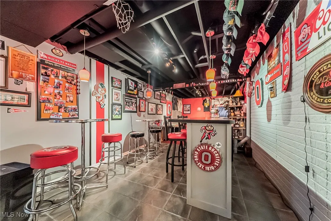 Indoor dry bar with dark countertops, decorative light fixtures, and dark tile patterned flooring