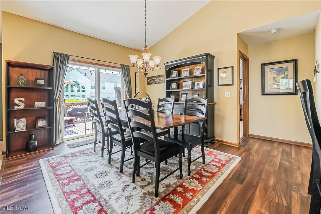 Dining area with vaulted ceiling, a chandelier, and dark wood finished floors