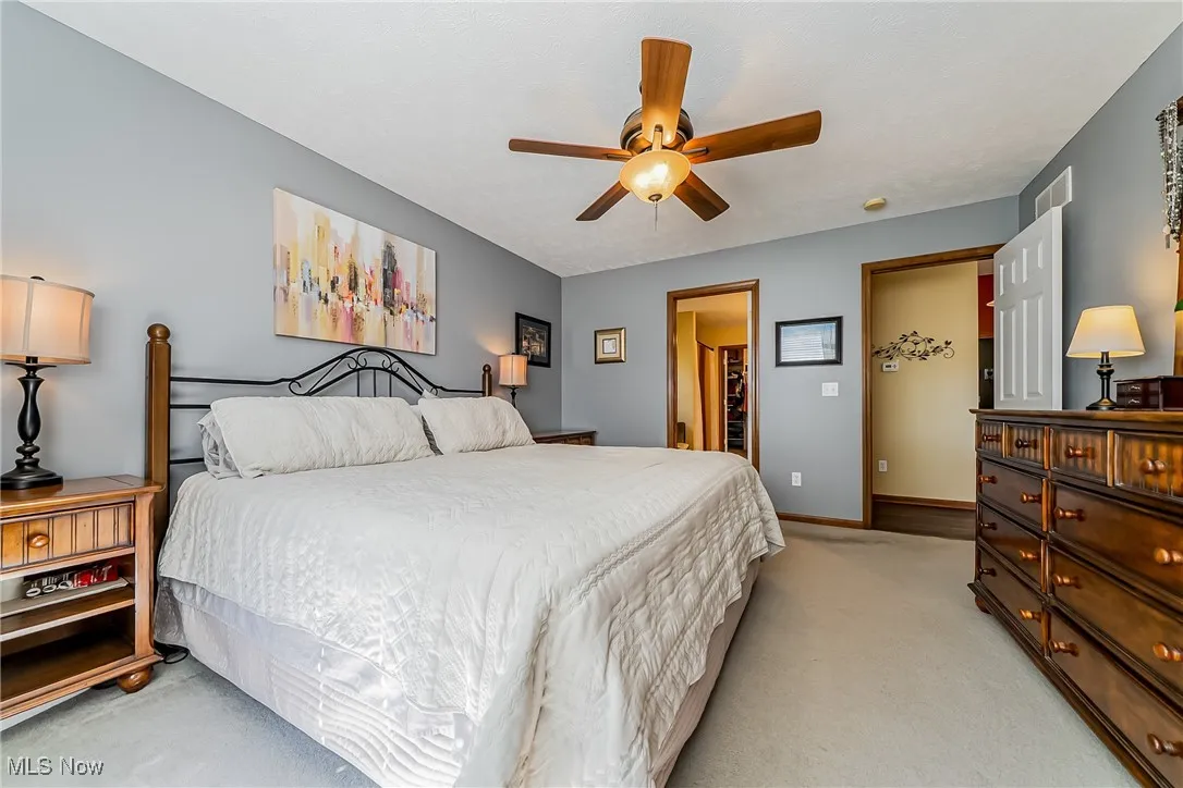 Bedroom featuring light colored carpet, a ceiling fan, and a walk in closet