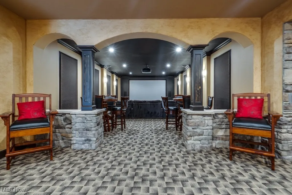 Home theater room with carpet, ornate columns, arched walkways, and recessed lighting