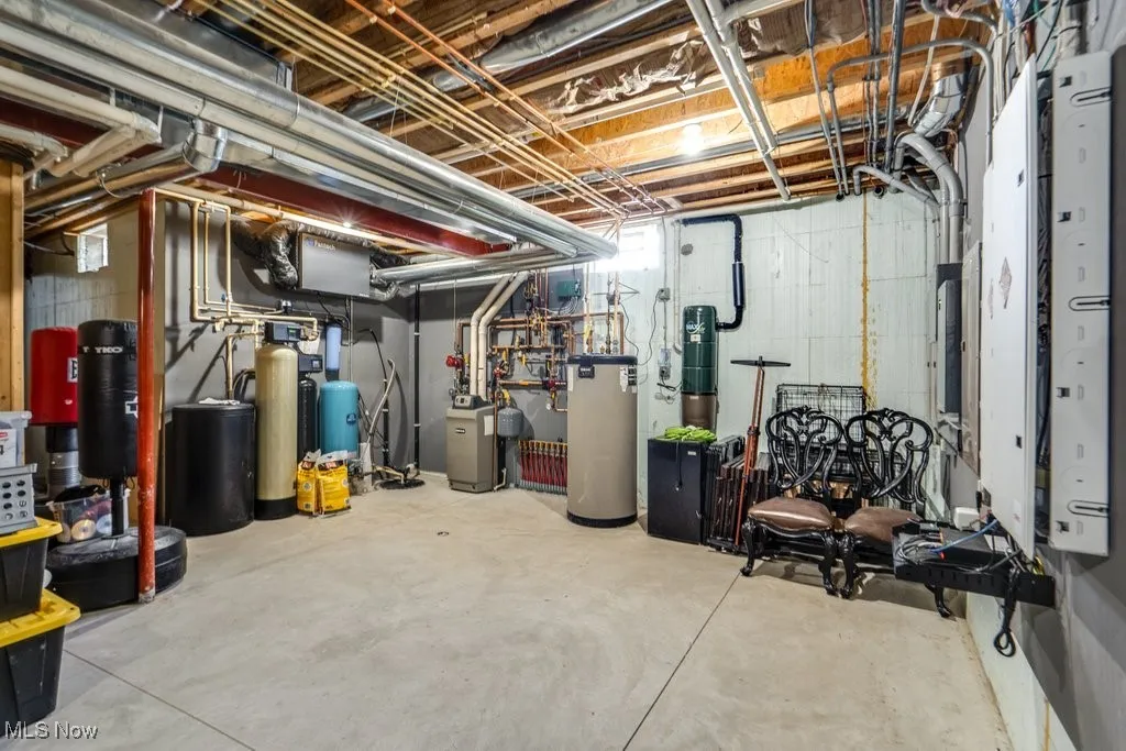 Unfinished below grade area featuring a water softener system and a water pressure tank