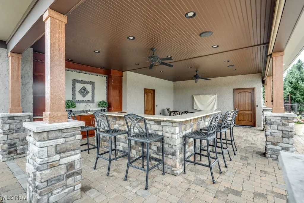 View of patio with a ceiling fan and exterior bar