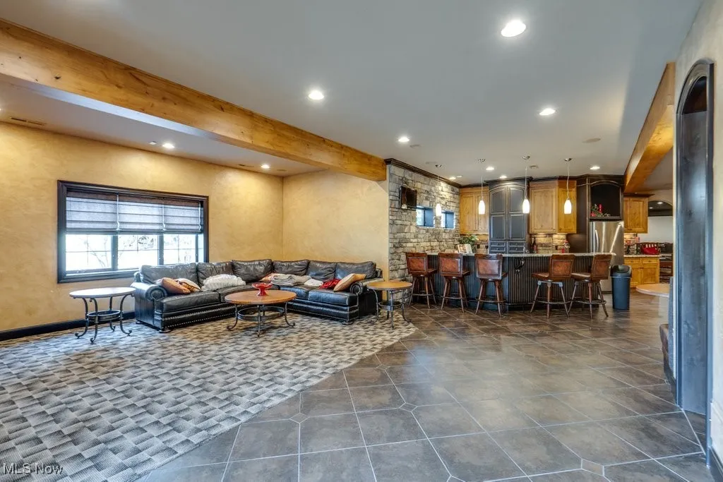 Living room featuring beamed ceiling, recessed lighting, and dark tile patterned floors