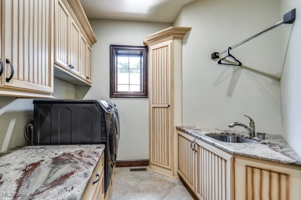 Washroom featuring cabinet space, light tile patterned flooring, and washing machine and dryer