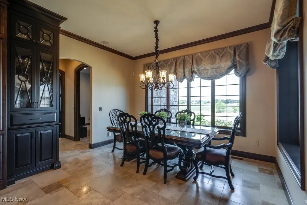 Dining area featuring crown molding, arched walkways, and a chandelier