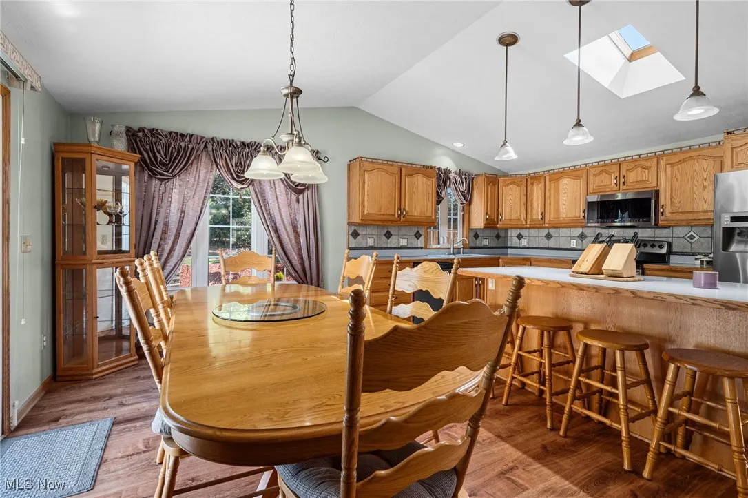 Dining room featuring vaulted ceiling, a skylight, and light wood-type flooring